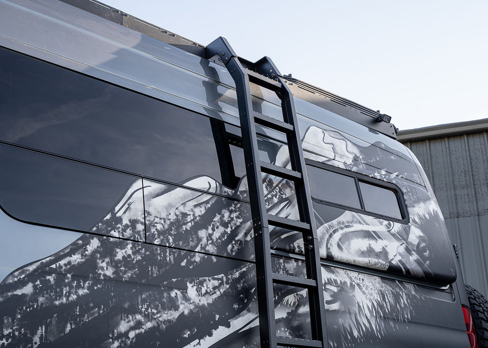 Middle-to-top view of ROAMBUILT Flatpack Ladder mounted on Mercedes Sprinter van, showing wide notched steps and aluminum side rails.