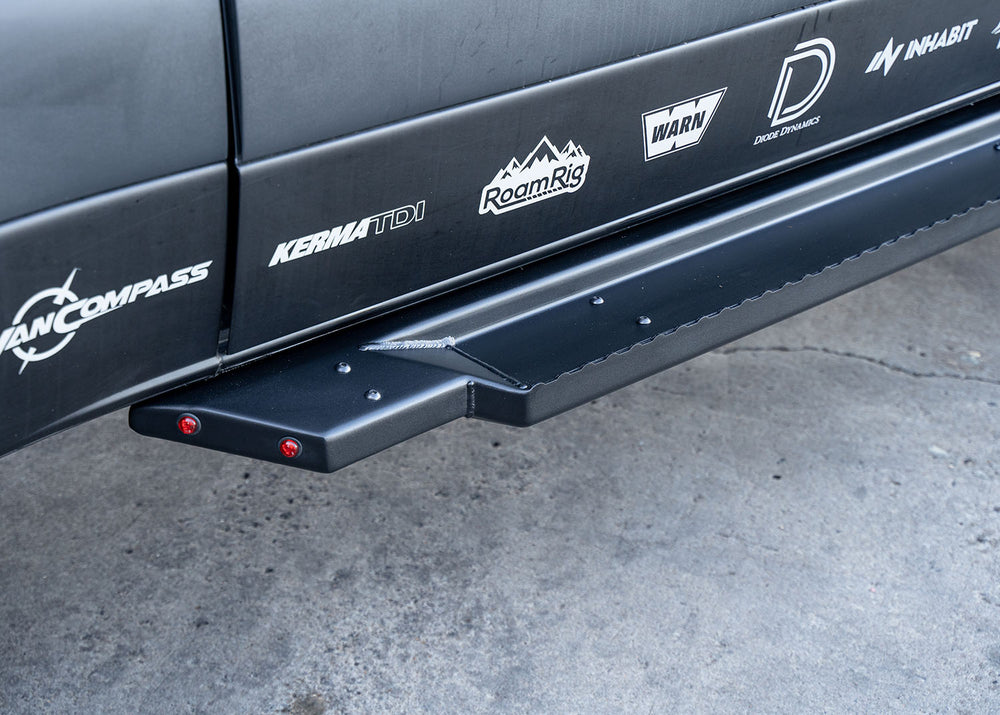 Close-up of rear section of ROAMBUILT Flat Side Step showing integrated small lights, raised grip edge, and black textured aluminum finish.