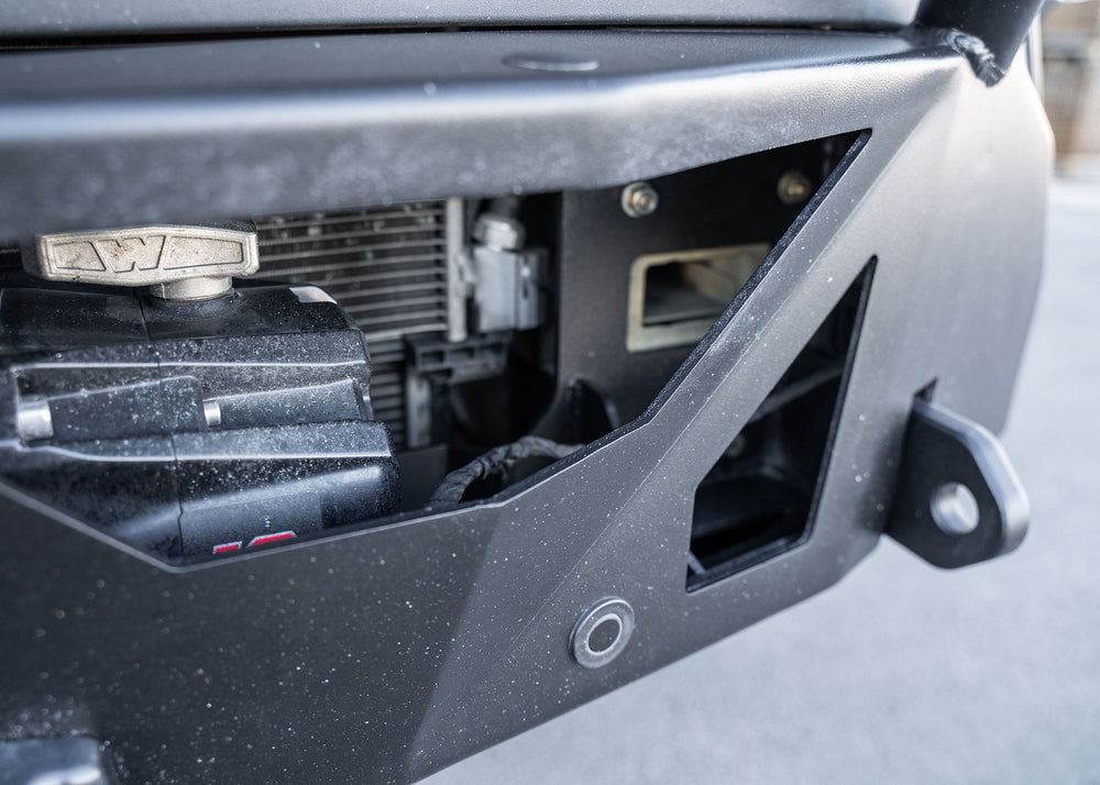 Close-up of the ROAMBUILT LoPro Front Bumper on a Mercedes-Benz Sprinter van, featuring a Warn VR-EVO winch with hawse fairlead, integrated parking sensors, and 1-inch thick steel shackle mounts, all encased within a lightweight 5052 aluminum outer shell.