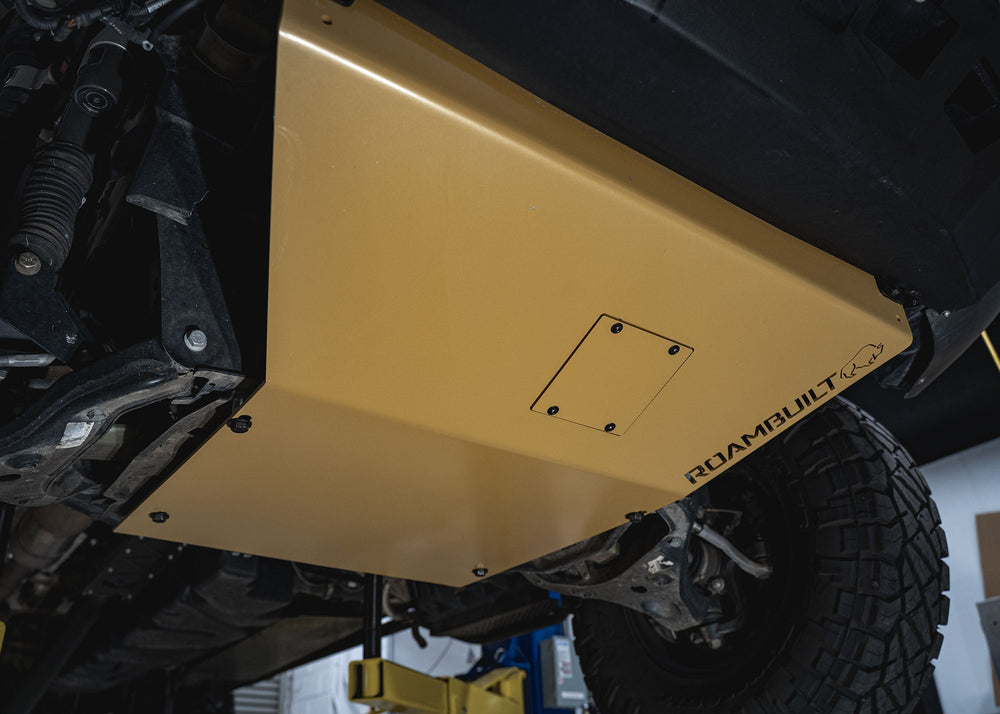 Underside view of the Mercedes Sprinter skid plate displaying the removable oil change access panel, full underbody coverage, mounting hardware, and connection points.